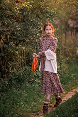 A girl walks along a rural road with carrots