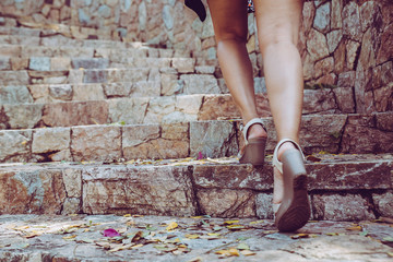 Young beautiful woman walking up the stone stairs with background. Step for success concept.
