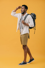 Fototapeta premium happy african american man gesturing while standing with backpack and searching on orange