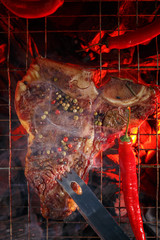 Raw t-bone steak is grilled on a grill over hot coals. Barbecue and grill. Top view.