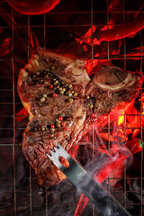 Raw t-bone steak is grilled on a grill over hot coals. Barbecue and grill. Top view.