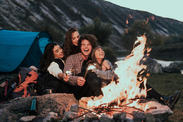 Beautiful teens with large white smile have a good time together at camping , playing with some lightning sparklers