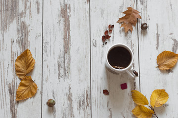 Cup of tea, autumn leaves on wooden table top view. Cozy autumn background. Copy space.