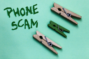 Text sign showing Phone Scam. Conceptual photo getting unwanted calls to promote products or service Telesales Three brown green vintage clothespins clear background Holding things