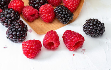 They look like artificial treats! But they are delicious and beautiful blackberries and fresh raspberries. Isolated on white background.