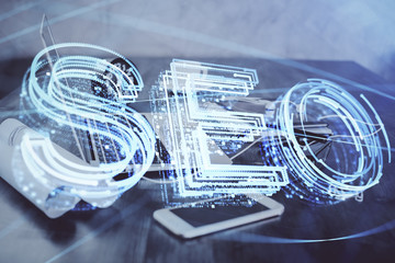 Double exposure of table with computer and seo drawing hologram. Search optimization concept.