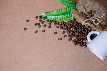 Close up coffee beans with coffee burlap bag and a white cup on old wooden background. Copy space for text.