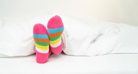 Female foot in warm stripe wool sock ,Woman sleeping and relaxing in bed concept. Warm and cozy...