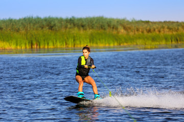 Young Sexy girl Catch waves on wakeboard when boat pulls a wakeboard 