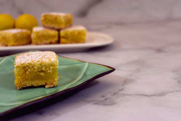 Home baked lemon squares, lemon bars, over minimal marble background with copy space 