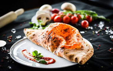 tasty italian calzone pizza with fresh ingredients and vegetables
