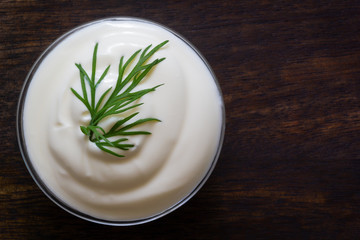 Yogurt or sour cream with fresh herb on wood background