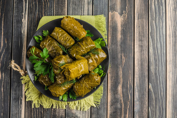 Delicious stuffed grape leaves (traditional doom Mediterranean cuisine Dolma) on a black plate with...