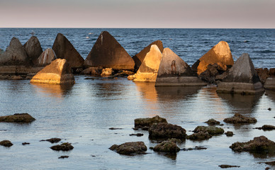 Seascape. Stones and concrete pyramids of light before sunset. Shabla, Northern Black Sea Coast, Bulgaria.