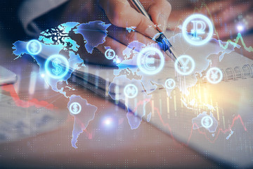 A woman hands writing information about stock market in notepad. Forex chart holograms in front....