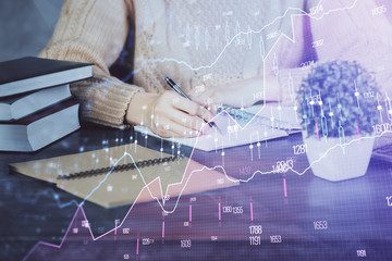 Forex graph on hand taking notes background. Concept of research. Double exposure