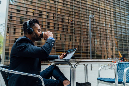 Indian Businessman Listening an Audiobook with the Headphones Ou