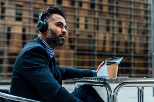 Indian Businessman Listening an Audiobook with the Headphones Ou