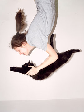The girl is holding a black cat
