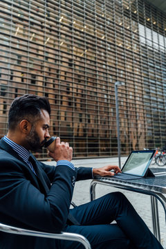 Elegant Adult Businessman Drinking a Coffee and working on His L