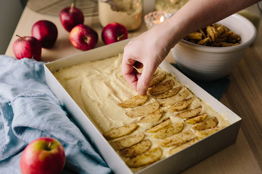 Woman laying apples slices coated in spiced sugar on cake