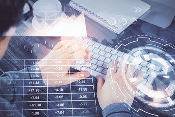 Multi exposure of graph with man typing on computer in office on background. Concept of hard work.