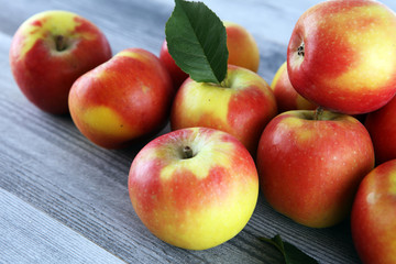 Ripe red apples with leaves on wooden background