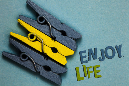 Conceptual hand writing showing Enjoy Life. Business photo text Any thing, place,food or person, that makes you relax and happy Gray yellow vintage clothespins clear background Holding things