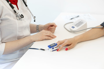 The doctor puts on the sensor measuring the pulse and oxygen in the blood on the patient's finger