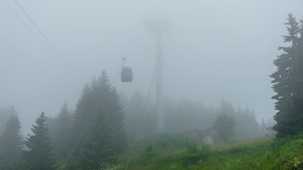 Cable car up in the sky in the forest in Sinaia, Romania, mountain view in rainy summer day