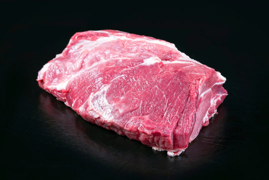 Row piece of Bosten butt pork offered as closeup on a black board