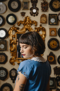 Portrait Of Stylish Tattooed Girl In Front Of The Wall With Clocks
