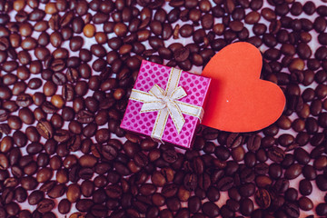 Valentine's Day concept. A pink gift box with red heart paper on coffee been background. Top view with copy space.