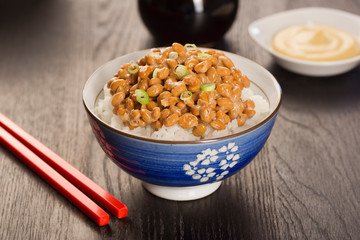 Bowl of Natto (Japanese Fermented Soybeans) on Rice with Soy Sauce and Mustard in Background	