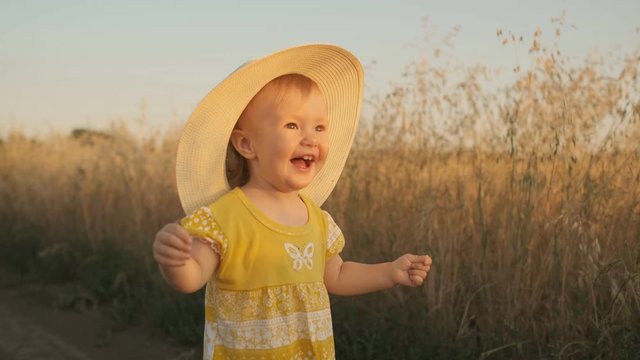 Happy little baby running across the field on a sunset summer day. Slow motion
