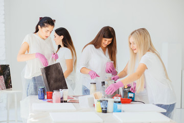 Creative woman painter dropping water on canvas while creating fluid acrylic abstract painting in art therapy class, hair dryer in her hand
