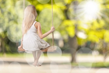 Little child blond girl having fun on a swing
