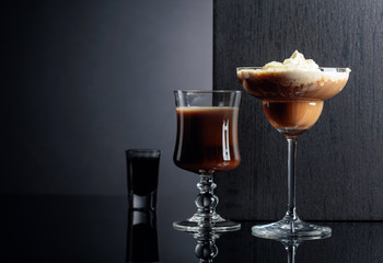 Coffee cocktails and liquor on black reflective background.