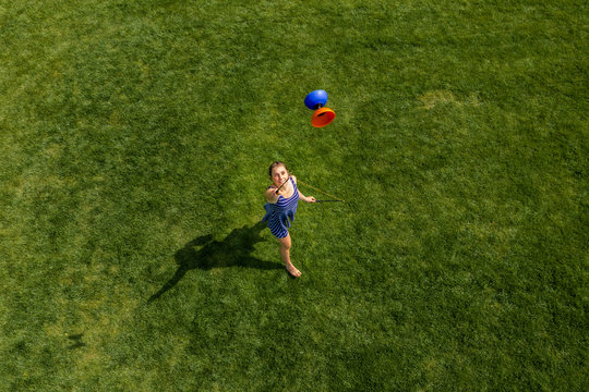 Aerial view of a young woman playing with a Diabolo on a meadow