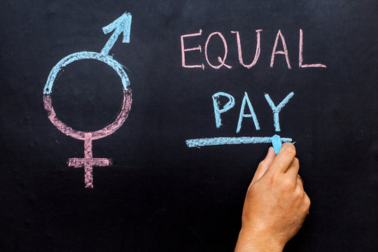 The pay gap and the symbol of gender equality are depicted on the chalkboard. Man's hand with chalk. The concept of gender equality.