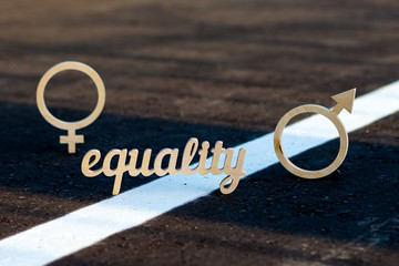 The concept of gender equality. Symbols of men and women of plywood on the pavement. The word equality is carved and plywood on asphalt.