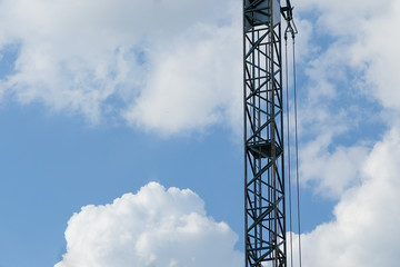 Construction crane part on a blue sky background with white clouds