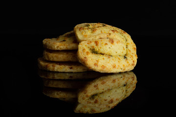 Group of four whole savory cheese palmier isolated on black glass