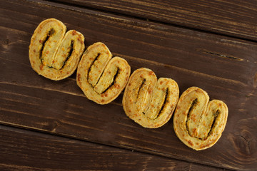 Group of four whole savory cheese palmier flatlay on brown wood