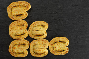 Group of six whole fresh savory cheese palmier flatlay on grey stone