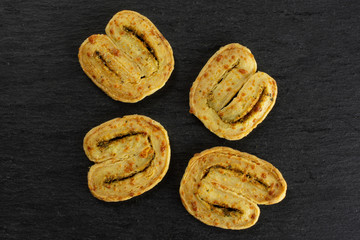 Group of four whole savory cheese palmier flatlay on grey stone
