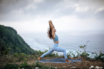 Girl practice yoga near ocean.