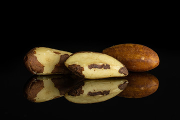 Group of three whole unshelled brazil nut isolated on black glass