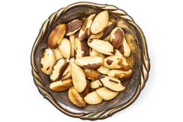 Lot of whole unshelled brazil nut in old iron bowl flatlay isolated on white background