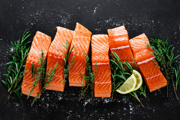 Salmon. Fresh raw salmon fish fillet with cooking ingredients, herbs and lemon on black background,...